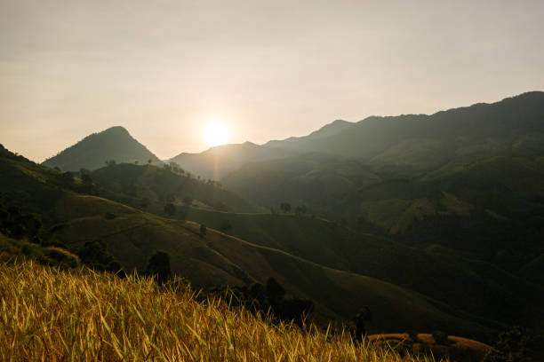 istock Golden sunlight illuminates rolling hills and mountains, creating serene landscape at sunset. warm glow enhances natural beauty of terrain, inviting tranquility,baanphawiang ,Pua,Nan, thailand 2181920157