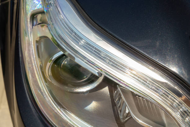A striking close-up of a black car headlight, showcasing its sleek design and illuminating power, perfect for automotive enthusiasts and commercial use.