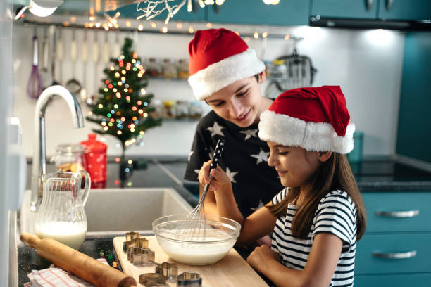 istock Children baking in kitchen wearing Santa hats, smiling 2181928676