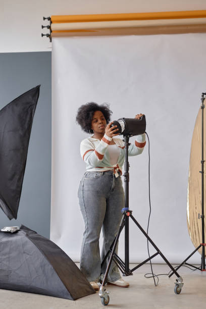 istock Black Female Photographer Setting Up Lighting Equipment 2181930287
