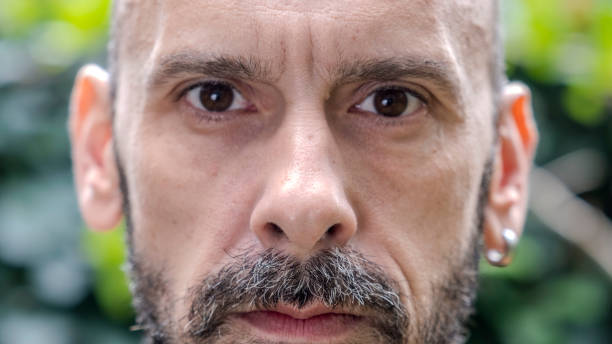 A headshot of a middle-aged man making funny facial expressions while looking at the camera