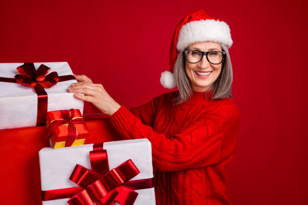 istock Photo of cheerful positive  grandma prepare presents stack shop wear specs hat pullover isolated red color background 2181937710
