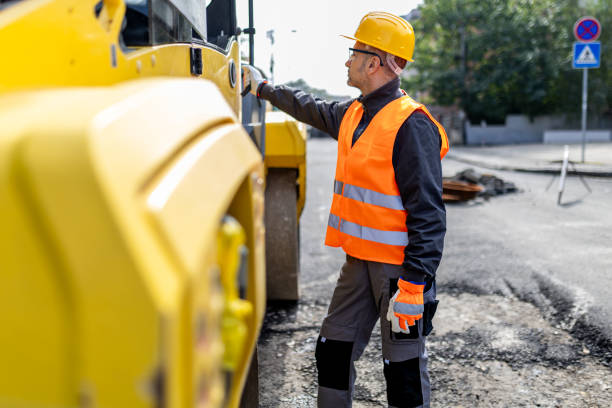 istock Construction worker inspecting heavy machinery on a road repair site during daylight in an urban area 2181938536