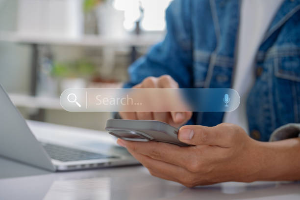 istock hands using a smartphone and laptop with a virtual search bar, symbolizing data search technology and SEO optimization in digital marketing. 2181938844