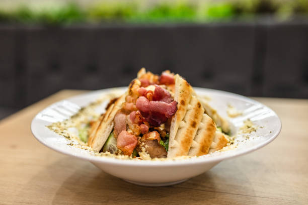 A mouthwatering bowl of grilled chicken salad topped with crispy bacon, drizzled with creamy dressing.