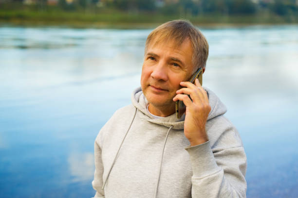 Man in hoodie with mobile phone resting after training in park.