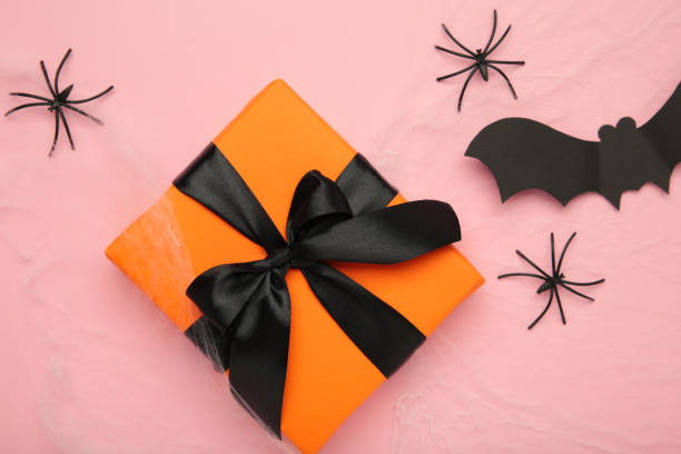 istock Halloween decoration concept. Artificial spider web decoration with spiders and gift on pink background. top view 2181943109
