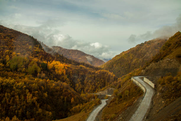 A stunning view features a winding road through majestic mountains, adorned with vibrant autumn colors. Beautiful landscapes of mysterious Svaneti, which is located in the north of Georgia.