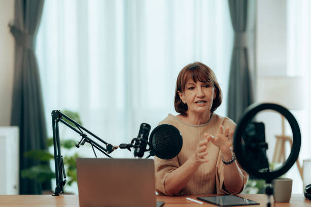 istock Senior Female Podcaster with Microphone and Laptop in Bright, Cozy Studio 2181950599