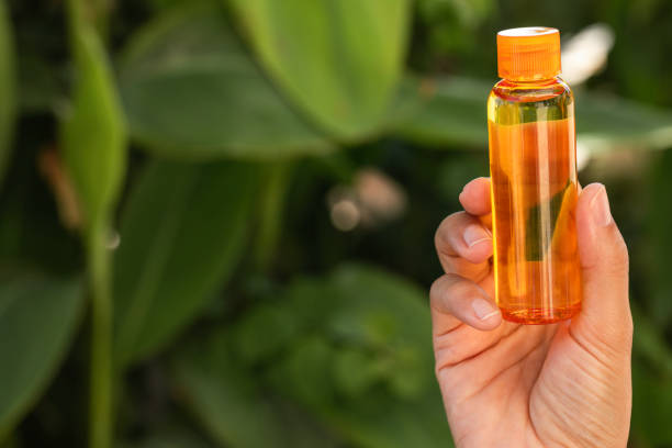 Hand is holding skincare oil . Tropical environment in background.