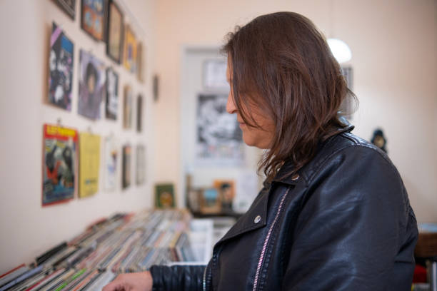 istock Record shops. A woman in a black leather jacket in a record store. 2181953477