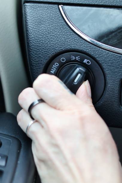 istock Low beam headlights - hand turning on the lights in the car 2181954227