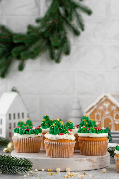 Christmas tree and wreath shaped cupcakes with candy sprinkles on top. Christmas dessert on a light concrete background.