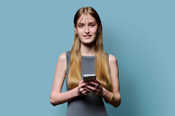 istock Young beautiful woman using smartphone on blue studio background 2181958243