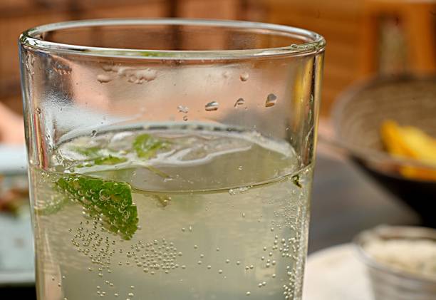 soft drink carbonated water with a green mint leaf in a transparent glass.