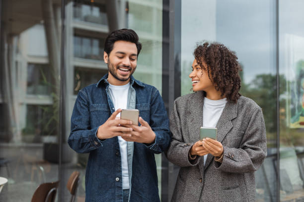 istock Smiling business people using smartphones while walking near office building 2181963622