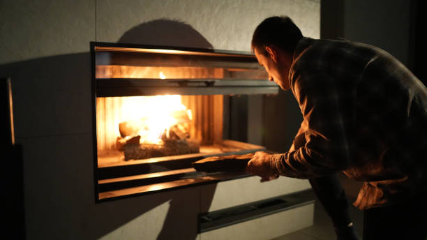 istock Man adding a log to a cozy fireplace, warming up the room on a chilly evening. 2181965179