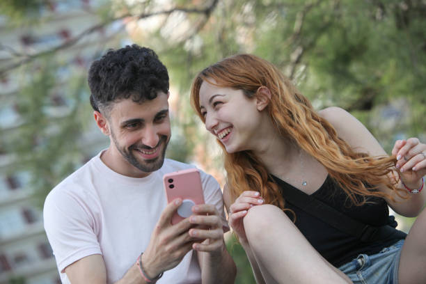 istock young happy couple with smartphone at the park 2181967340