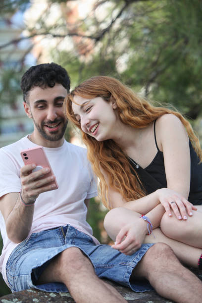 istock young happy couple with smartphone at the park 2181967362