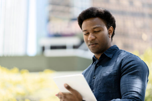 istock Focused businessman reading information on tablet outdoors in urban setting 2181975228