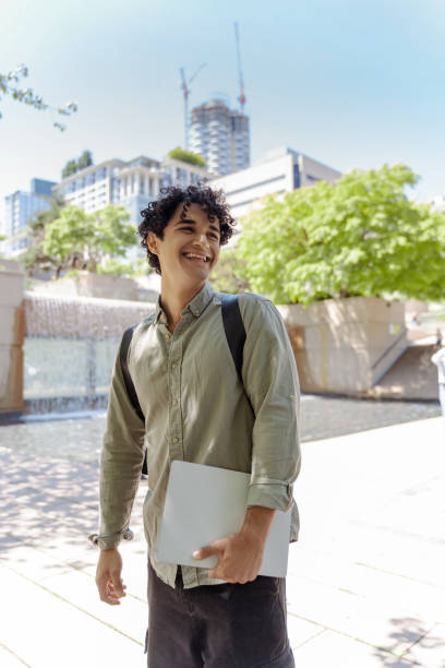 istock Student walking with laptop outside enjoying campus life 2181975395