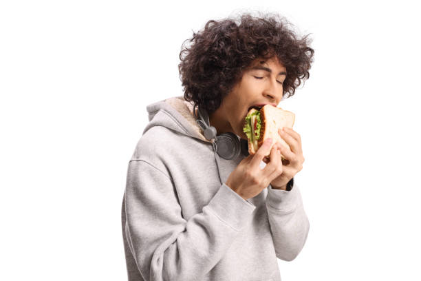 Happy young man with headphones eating a sandwich