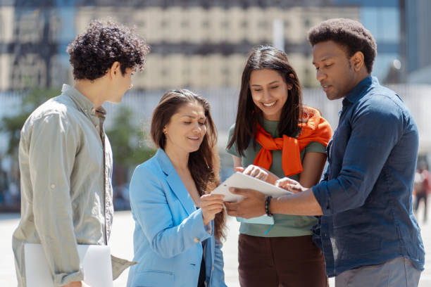 istock Group of young professionals collaborating using digital tablet outdoors in the city 2181975715