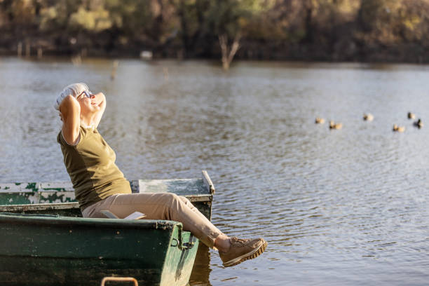 istock Senior Woman Relaxing on a Boat in Peaceful Lake Setting 2181978303