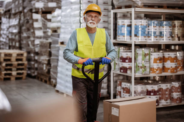 istock Senior Worker With Fork Pallet Truck Stacker in the Warehouse 2181982618