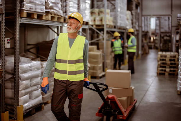 istock Senior Worker With Fork Pallet Truck Stacker in the Warehouse 2181982699