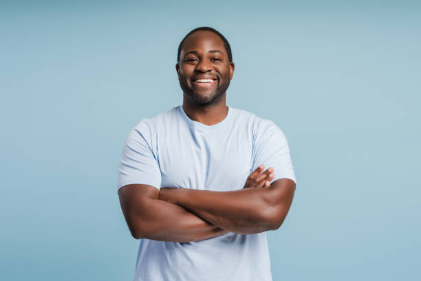 Happy young African American man posing with arms crossed in studio
