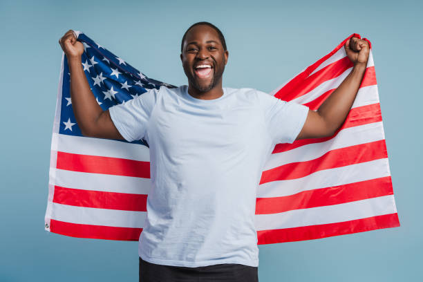 istock Happy handsome African American man standing with USA flag in studio 2181983005