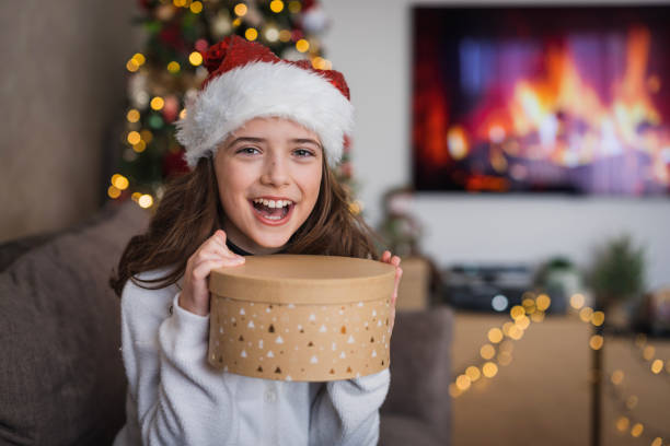 Cute teenage girl holding a gift box and wearing a Santa hat