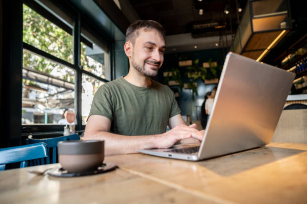 istock Mid adult man using laptop on a coffee shop 2181984167
