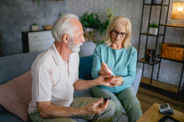 istock Senior couple using lancet on finger for checking blood sugar level 2181985433