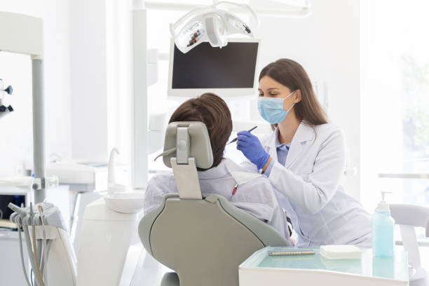 istock Young female dentist making treatment to patient 2181986650