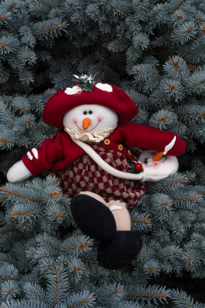 istock Christmas snowman sitting in a pine tree 2181991381