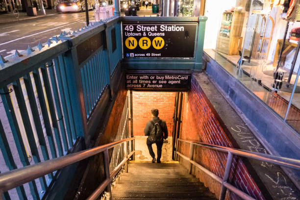 New York City, NY - USA: View down into lighted subway station in Manhattan at night with man on stairs