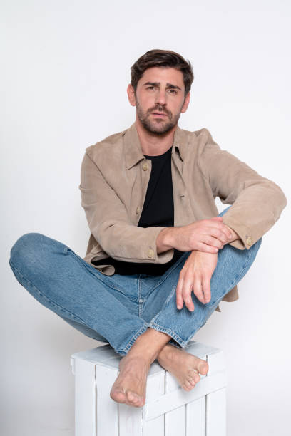 istock Handsome man sitting barefoot on white crate wearing casual clothes 2182002042