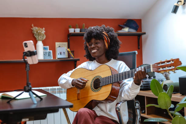 istock Happy woman playing guitar while recording with smartphone 2182002138