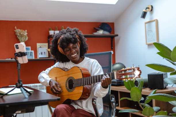 istock Happy woman playing guitar while recording with smartphone 2182002140