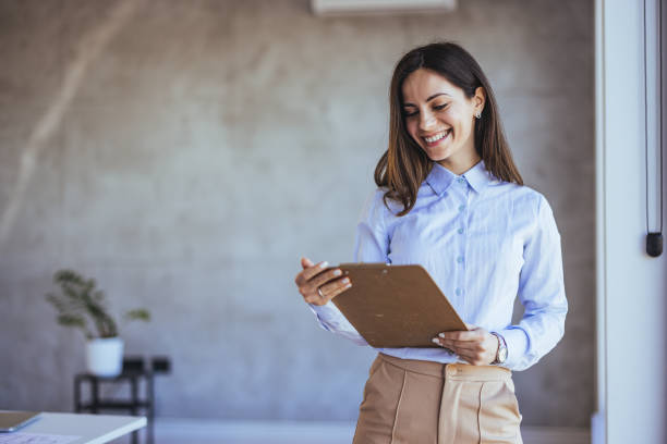 istock Confident Businesswoman Smiling While Holding a Clipboard 2182007495