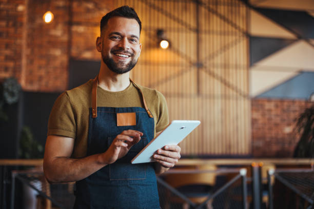 istock Smiling Young Barista Using Tablet in Modern Cafe 2182007791
