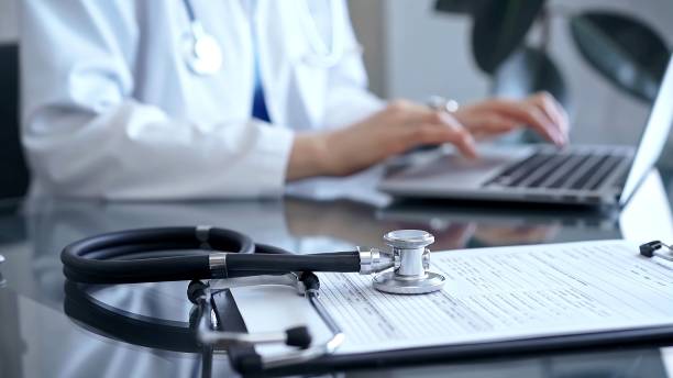 istock Stethoscope and medication record form are on the table besides the working doctor. Workplace in Medicine and Health care 2182009972