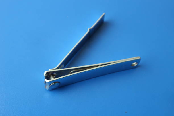 Close-up of a woman's hands using a nail clipper to trim fingernails. The image focuses on personal grooming and hygiene at home, with natural light and relaxed atmosphere. Concept: nail care, self-care, health, routine, body maintenance.