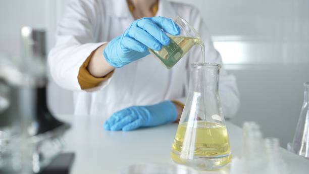istock A scientist, wearing a lab coat and blue protective gloves, is pouring a yellow liquid from one beaker to another in laboratory, close up. Medicine and science concepts 2182015321