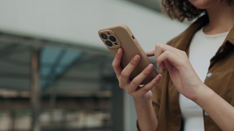 Close Up View of the Hands Holding Cell Phone and Chatting in Social Media while Standing Outdoors.