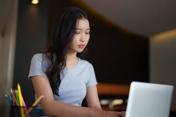 istock Asian teenage student woman typing and researching data on laptop for doing assignment homework after reading a book and watching lecture video online lesson to studying education knowledge in cafe 2182020903