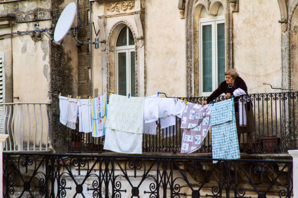 Monterosso Almo, Sicily: A senior woman hangs laundry on a balcony in Monterosso Almo, a village in Ragusa Province in Southeast Sicily.