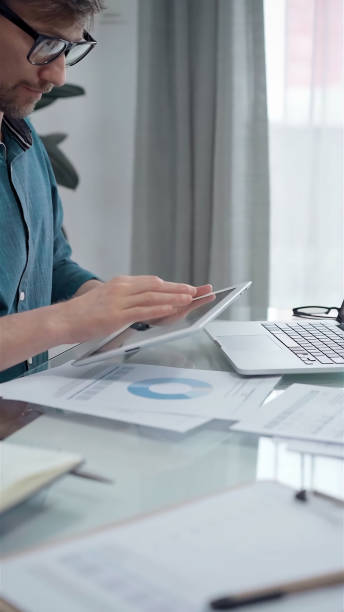 istock Businessman wearing green shirt and glasses is working with tablet computer and data analysis charts. Vertical business portrait 2182021310